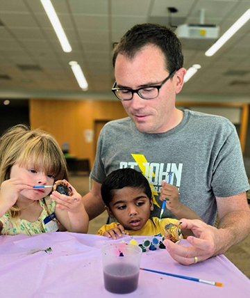 Man compleing an art project with his two children..