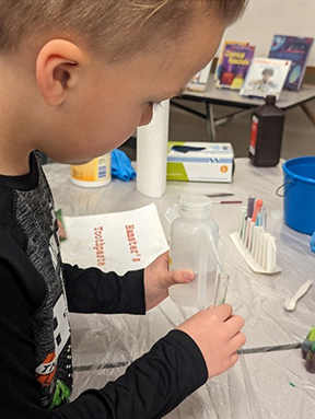 Child putting liquid into a test tube.