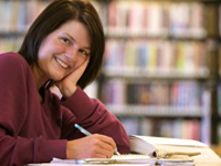 A woman smiling while reading a book.